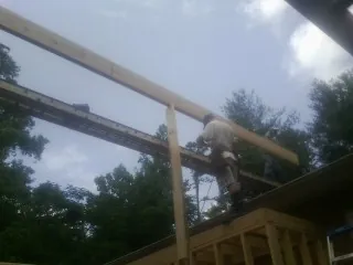 Carpenter setting a ridge beam over a new addition frame — Ice Dam Removal by Roofing Brothers in Copemish