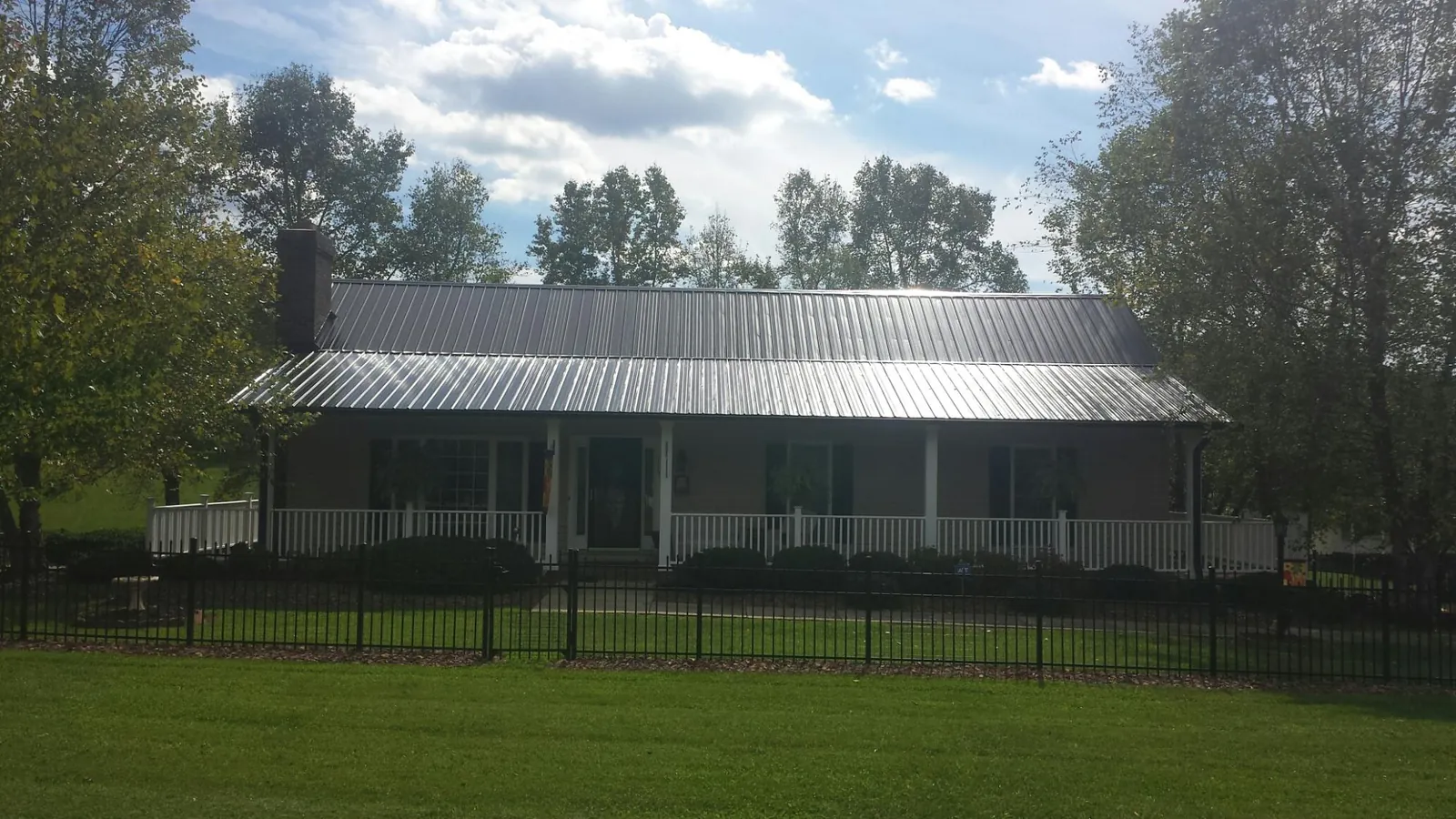 Gray metal roof on a brick ranch with a full width front porch — Gutter Guard Installation work by our crew in Copemish