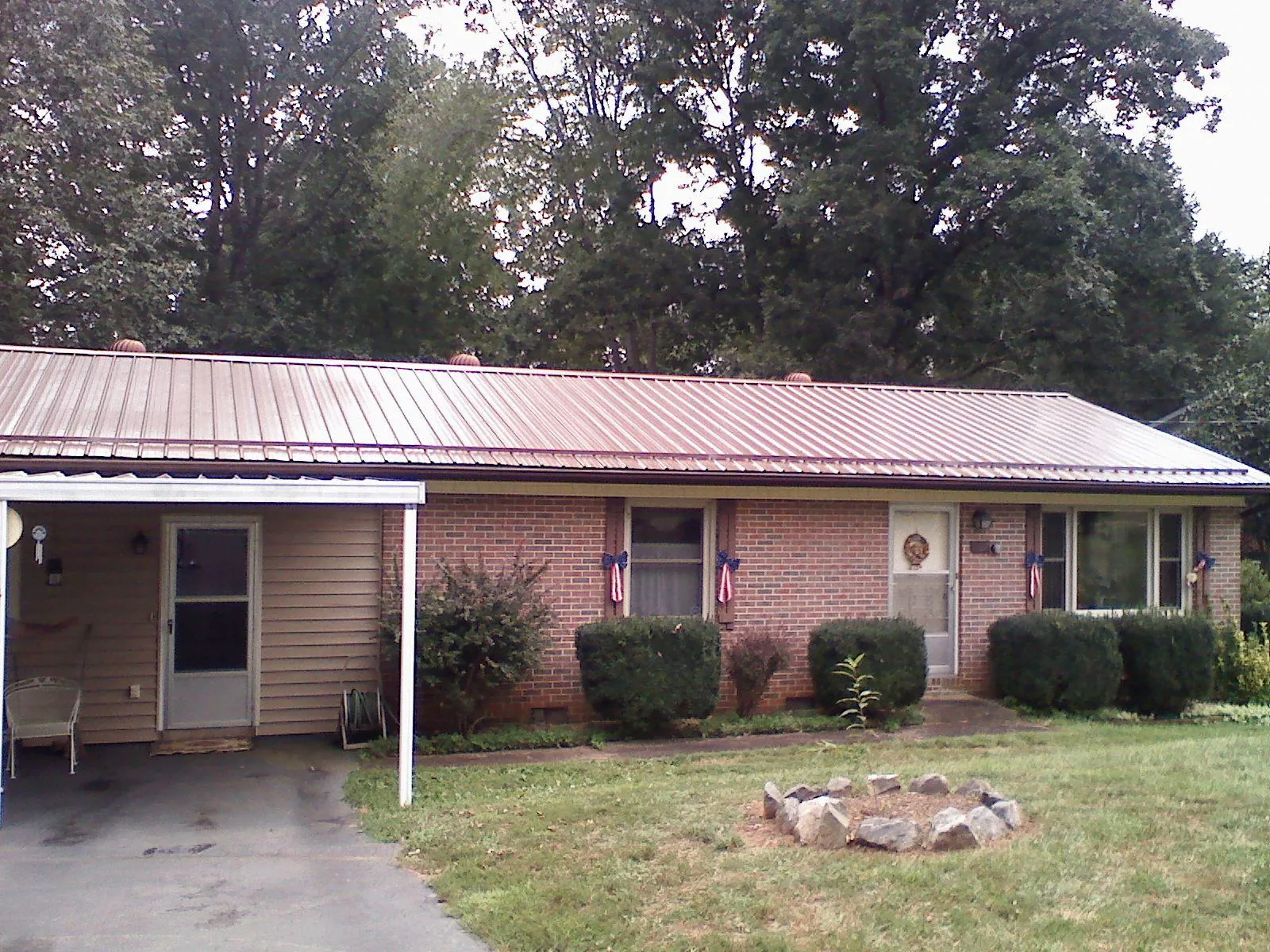 Bronze metal roof and carport on a brick ranch home — Roof Repair work by our crew in Copemish